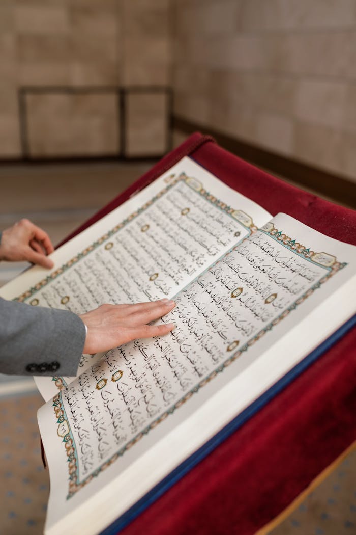 Close-up of a person engaging with an open Quran during Ramadan inside a mosque.
